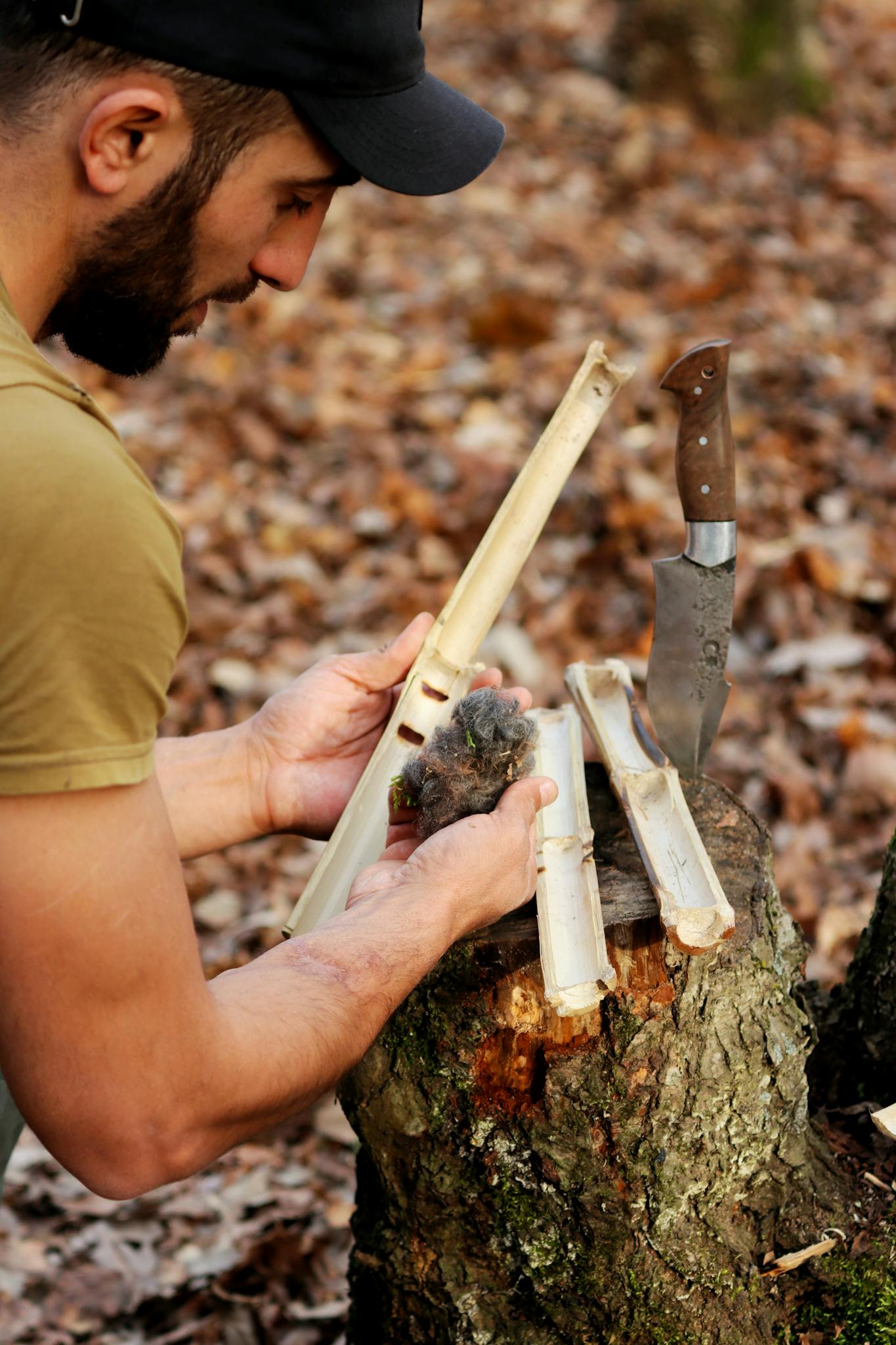 A man in Azerbaijan uses a knife to prepare wood for starting a fire, showcasing survival skills.